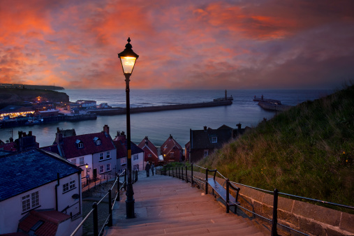 Whitby is a seaside town, port and civil parish in the Borough of Scarborough and English county of North Yorkshire. Prior to local government reorganizations in the late 1960s it was considered to be part of the North Riding of Yorkshire. Situated on the east coast of Yorkshire at the mouth of the River Esk, Whitby has an established maritime, mineral and tourist heritage. Its East Cliff is home to the ruins of Whitby Abbey, where Caedmon, the earliest recognized English poet, lived. The fishing port emerged during the Middle Ages and developed important herring and whaling fleets, and was (along with the nearby fishing village of Staithes) where Captain Cook learned seamanship.