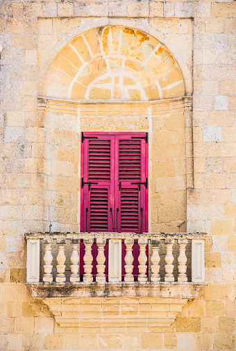 arched balcony with traditional Maltese colorful door in Mdina