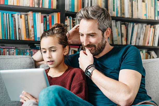 istock bearded dad  with daughter looking at  digital tablet on couch 489112340