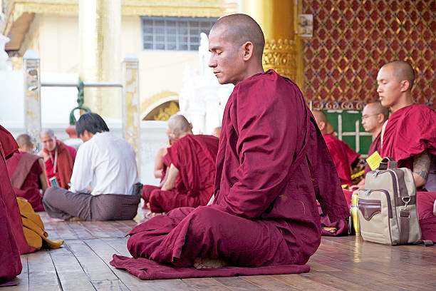 Yangon, Myanmar - February 15, 2015: Buddhist monk in traditional robes in meditation at the Shwedagon Pagoda, a gilded stupa located in Yangon, Myanmar. The pagoda is the most sacred Buddhist pagoda in Myanmar.