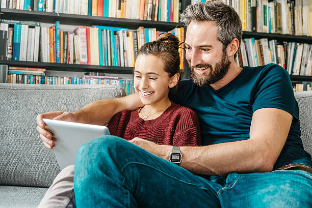 父と娘の楽しみ、デジタルタブレット上のソファー - digital tablet looking child offspring ストックフォトと画像