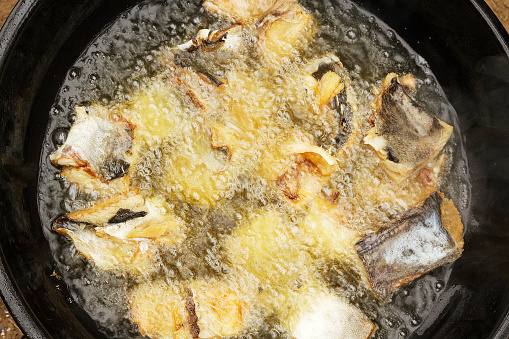 Colour photograph of fried fish, in the process of frying in very hot oil. This is traditional African Congolese cooking.