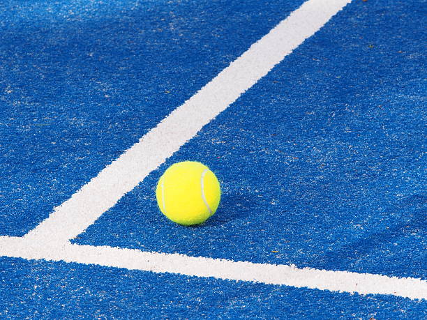 Tennis balls in hard sunlight on synthetic court surface