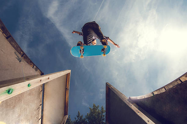 Below view of a young skateboarder in Ollie position. Directly below view of a young man on skateboard at skate park. x games stock pictures, royalty-free photos & images