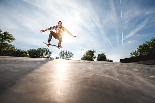 Low angle view of a young man skateboarding and looking at the camera.