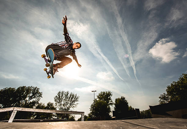 Extreme skateboarder in Ollie position against the sky. Low angle view of young extreme skateboarder practicing at the park. x games stock pictures, royalty-free photos & images