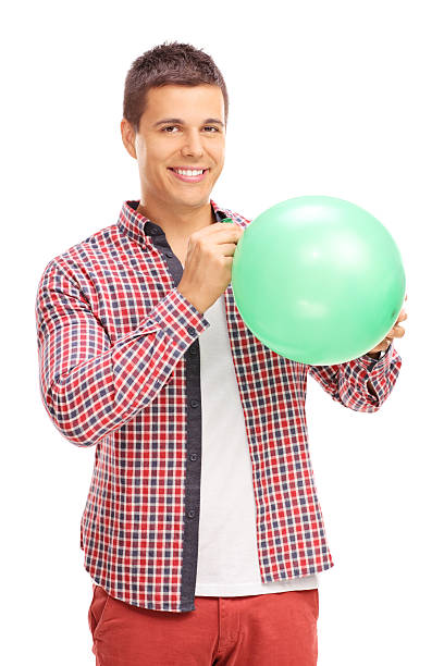 istock Young man blowing up a green balloon 489117496