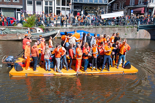 Amsterdam, the Netherlands - April 27, 2015: People in orange celebrate King's Day along the Singel canal on the raft.