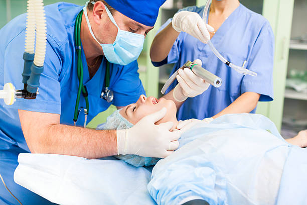anesthesiologist medical doctor working with anesthesia patent anesthesiologist medical doctor work anesthesia breathing mask check for throat, woman patient lying in operating surgery room, hospital equipment emergency room photos stock pictures, royalty-free photos & images