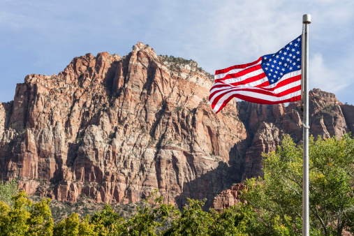 An American flag with Sierra Nevada mountain range in California in the background.
