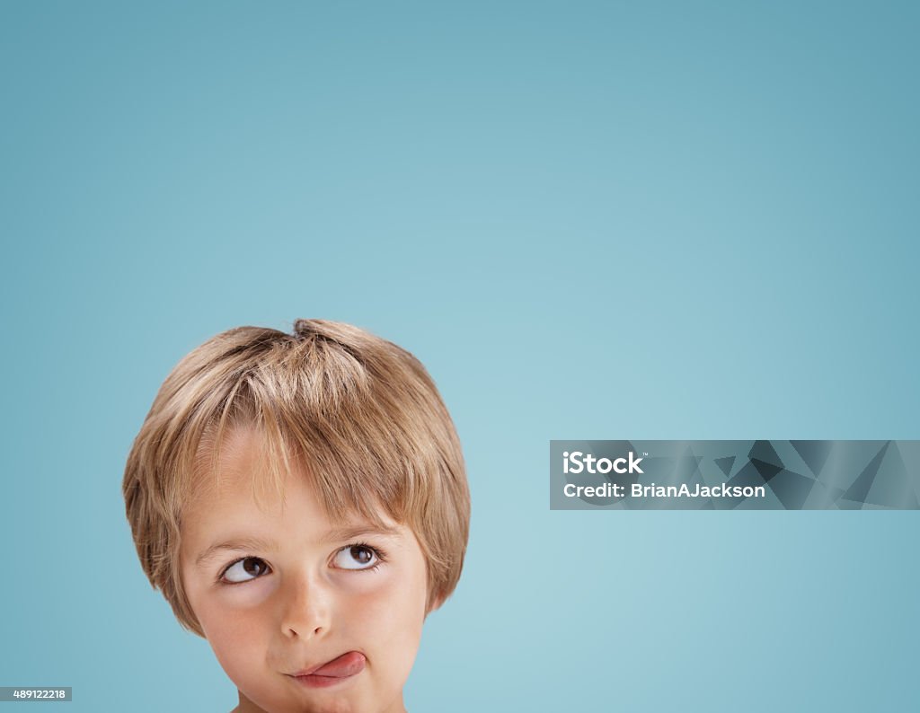 Boy looking up with tongue out licking his lips Boy with tongue out licking his lips looking up at copy space for a message or product placement Child Stock Photo
