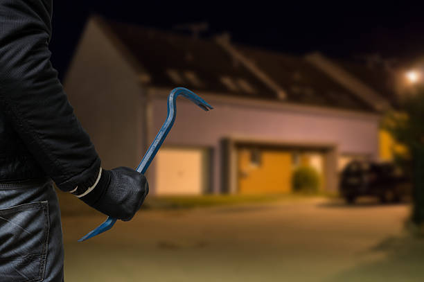 Burglar or robber with crowbar stands in front of house Crime concept. Burglar or robber with crowbar stands in front of the house at night. burglar stock pictures, royalty-free photos & images