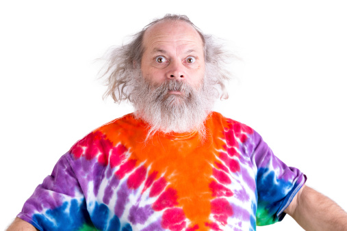 Cute grey long hair and beard senior man so surprised that his eyes came out, he is wearing a tie dye colorful T-shirt