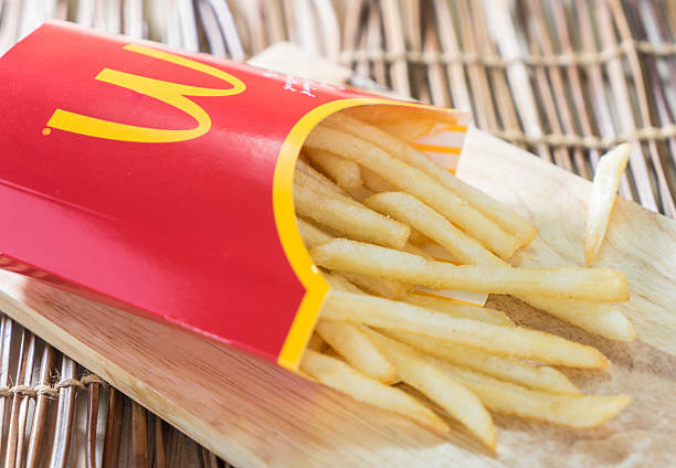 Mc Donalds French Fries Bangkok, Thailand - September 19, 2015: A box of Mc Donalds French Fries on a wooden tray. MCDONALDS FRIES stock pictures, royalty-free photos & images