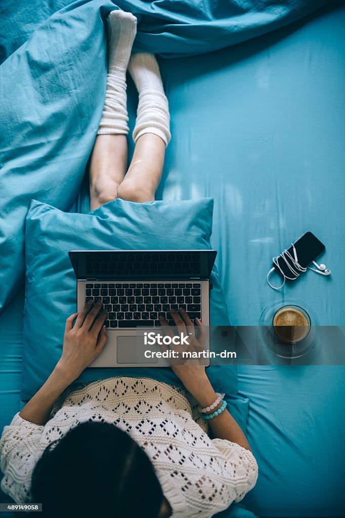 Girl in bed with lap top Woman in bed using lap top and drinking coffee Bed - Furniture Stock Photo