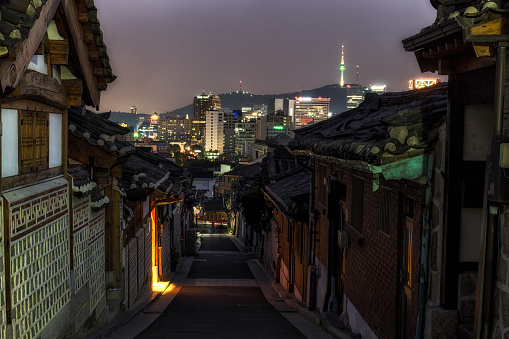 bukchon hanok village sunset view through the famous alleyway with the view of n seoul tower in the distance.  Taken in Seoul, South Korea