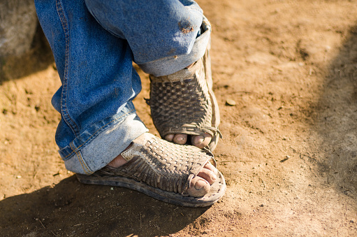 A Mexican worker's feet in standing position showing a relaxed state after a long day's work in the field using traditional huaraches.