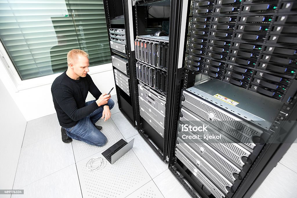 IT consultant calling for help in datacenter It engineer or technician searching on the phone for help to solve problem with a server in data rack. Shot in datacenter. 2015 Stock Photo