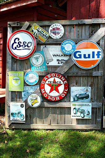 Gloucester, Va. USA  - August 16, 2015:   Hanging on an old barn door are vintage signs from the gas and oil industry including Texaco, Gulf, Esso, Buick and Pontiac, most signs from the American Motor industry.