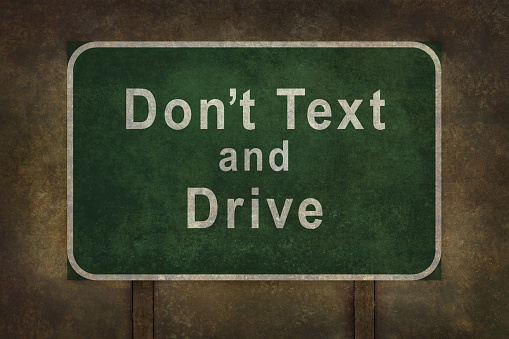 Don’t Text and Drive  road sign illustration, with foreboding background