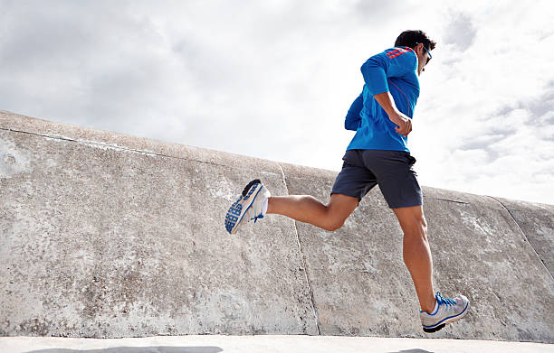 Feeling good and keeping fit! Rearview shot of a sporty young man running outdoors running jogging men human leg stock pictures, royalty-free photos & images