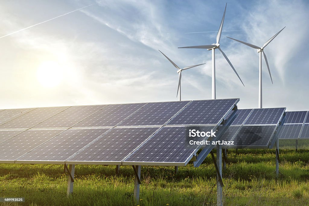 Paneles solares y generador de viento en el cielo azul en la puesta de sol - Foto de stock de Panel Solar libre de derechos