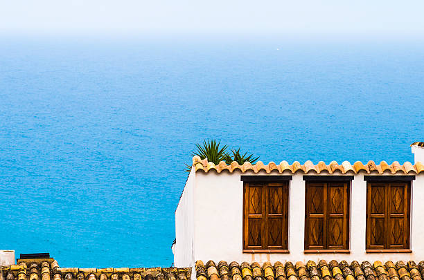 Wood windows on a house in the old part of the resort town of Altea in Spain. In the background the Mediterranean Sea