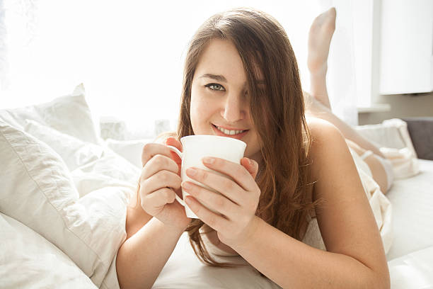 istock smiling woman drinking coffee in bed at morning 489197281