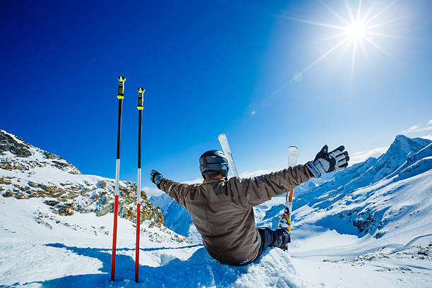 happy alpine skifahrer sitzt auf dem rand - ski skiing european alps resting stock-fotos und bilder