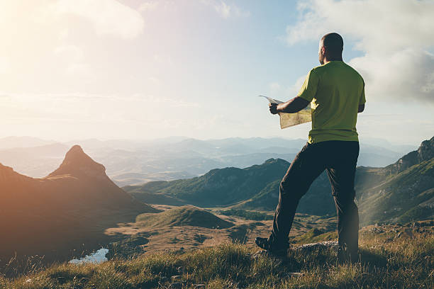Finding the way. Finding the way. Man with a map standing on top of the mountain, looking ahead. pursuit concept stock pictures, royalty-free photos & images