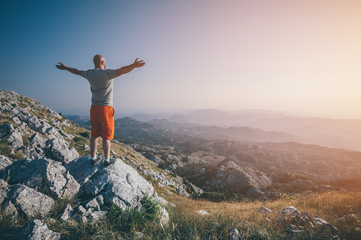 Freedom. Man jumping in the air with mountain landscape on background.