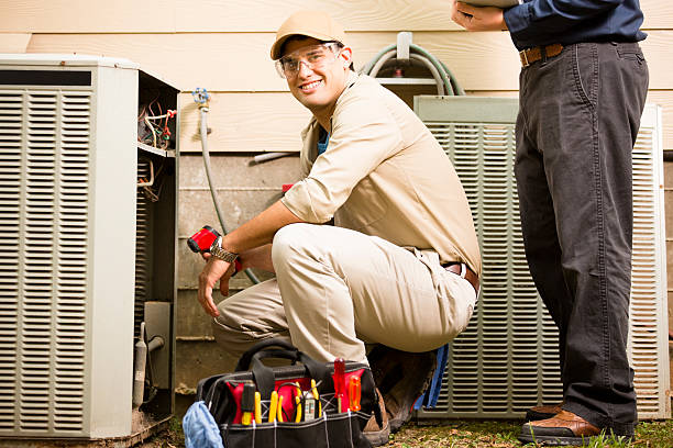 Air conditioner repairmen work on home unit. Blue collar workers. stock photo