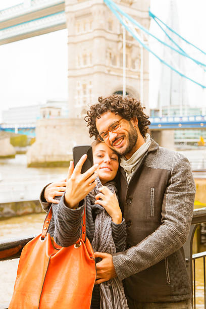 Young Couple hugging making selfies with smart phone in London Couple in London are taking pics and have fun. Tower Bridge behind them. the shard close up stock pictures, royalty-free photos & images