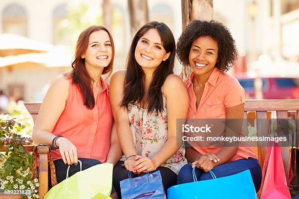 Três Mulheres Amigos Com Sacos De Compras Sentado No Centro Comercial - Fotografias de stock e mais imagens de 20-29 Anos