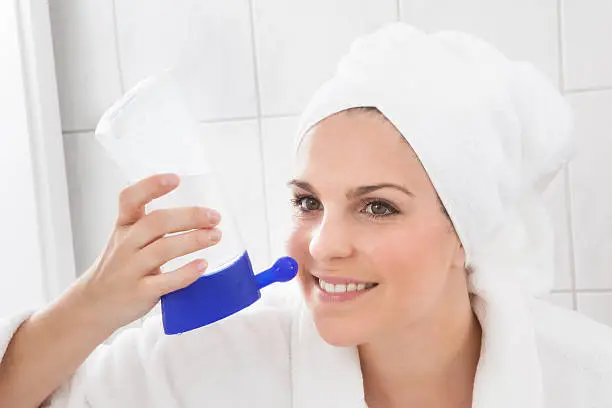 Young Beautiful Woman Cleaning Nose In Bathroom