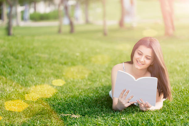 istock Relaxed, young woman reading book on green grass 489226121