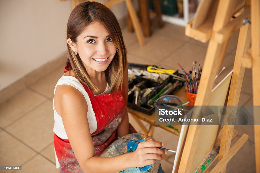 Happy female artist at work Portrait of a gorgeous young female artist working on her most recent art project in a studio and smiling 2015 Stock Photo