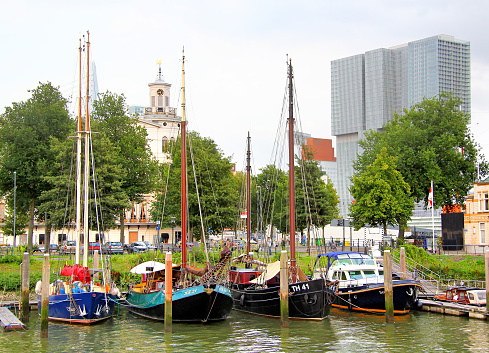 Rotterdam, Netherlands - August 9, 2014: View of the three sailing boats moored in the harbor at the background of the modern office building.