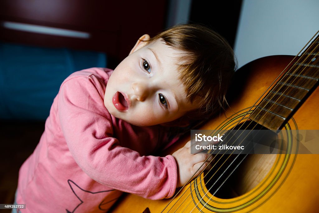 Small toddler listening to sound of a guitar Small toddler listening and singing to sounds, coming out of a guitar. Musical education, tactile experiences and learning concept. Sensory Perception Stock Photo