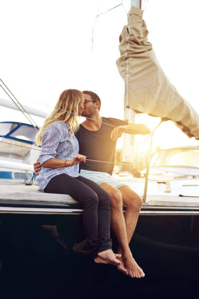 Sweet Young Couple Kissing at the Yacht Deck Sweet Young Couple Kissing at the Yacht Deck During Sunset Time. couple punting stock pictures, royalty-free photos & images