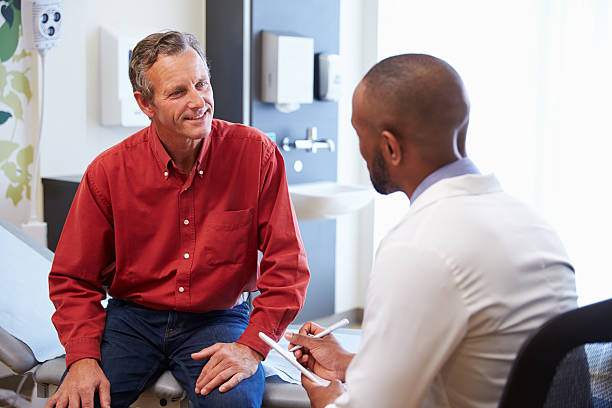 Male Patient And Doctor Have Consultation In Hospital Room Male Patient And Doctor Have Consultation In Hospital Room mid adult stock pictures, royalty-free photos & images