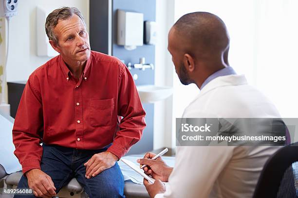 Male Patient And Doctor Have Consultation In Hospital Room Stock Photo - Download Image Now