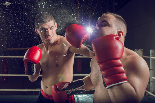 Two men boxing. One fighter is receiving a punch in the face.