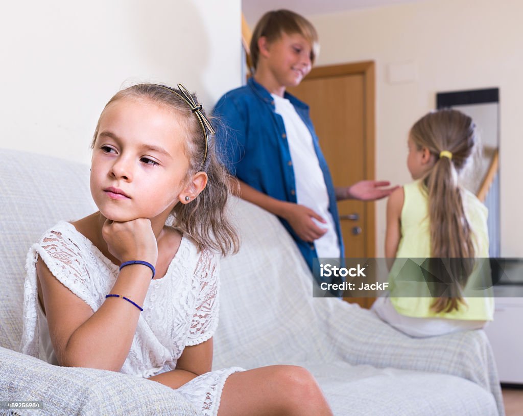 First amorousness:  girl and couple of kids apart First amorousness: unhappy american girl and couple of kids apart indoors 2015 Stock Photo