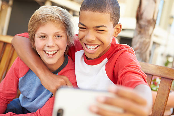 dos niños sentado en el banco en el centro comercial tomando autofoto - pre teen boy fotografías e imágenes de stock