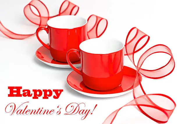 red cups with redribbon on a white background. valentine's day card concept