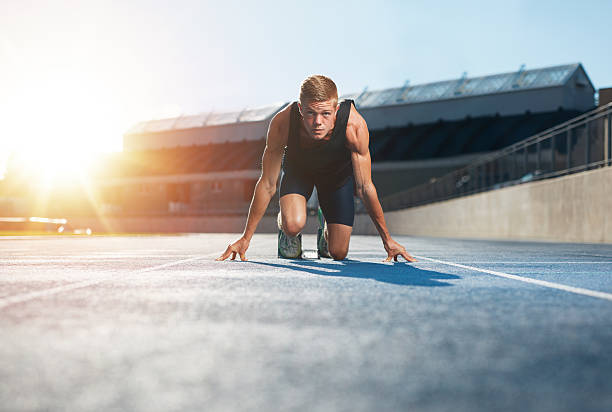 atleta en posición inicial listos para iniciar una carrera - esprint fotografías e imágenes de stock