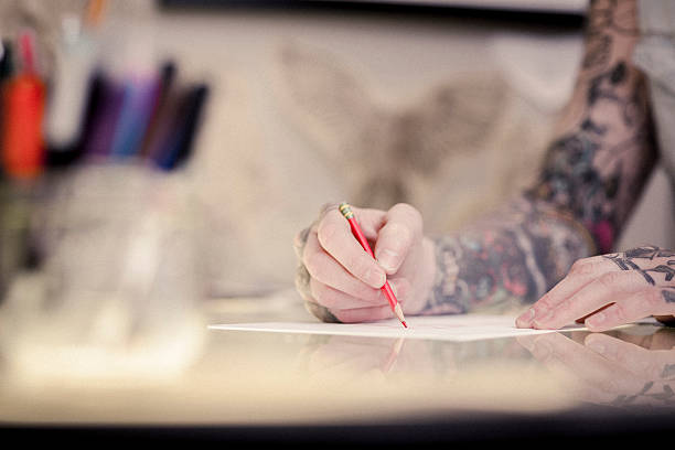 istock Professional's tattooed hands drawing on paper 489304926