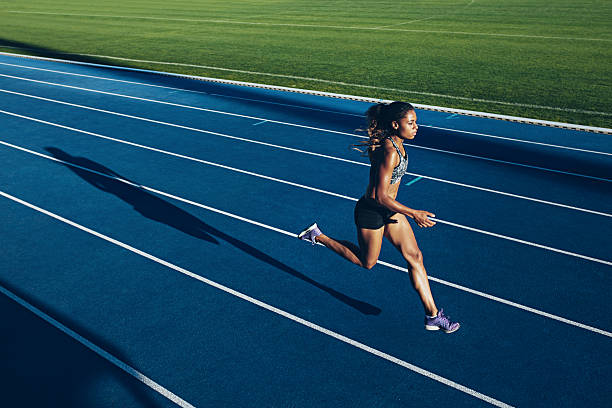 African woman running on racetrack Outdoor shot of young African woman athlete running on racetrack. Professional sportswoman during running training session. track and field athlete stock pictures, royalty-free photos & images