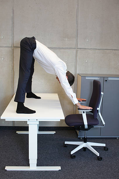 istock flexible business man  practicing yoga on desk in his office 489307672